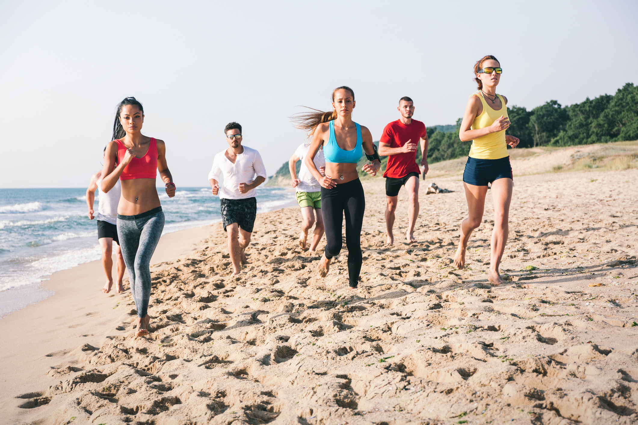 Large group of young people jogging at the beach at sunrise